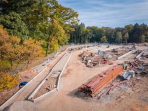 Widok z góry na plac budowy pętli tramwajowej na Sępolnie z hałdami ziemi i materiałami budowlanymi.