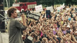 Jan Borysewicz śpiewający do mikrofonu na koncercie zespołu Lady Pank przed tłumem fanów.
